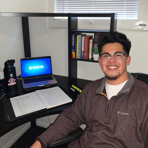 Victor working safely from his desk at home as he prepares for his day as a Merrill Lynch Wealth Management intern.