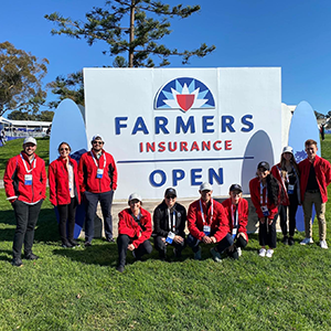 Students from the SMBA '22 class standing in front of the Farmers Insurance Open sign