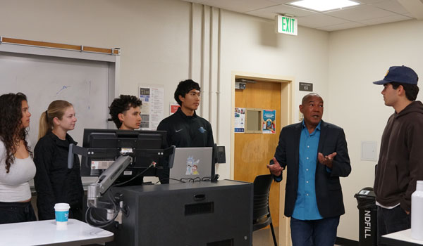 SDSU marketing lecturer, Sean McHenry (second from right)  discusses the day’s lesson plan with his students prior to class.